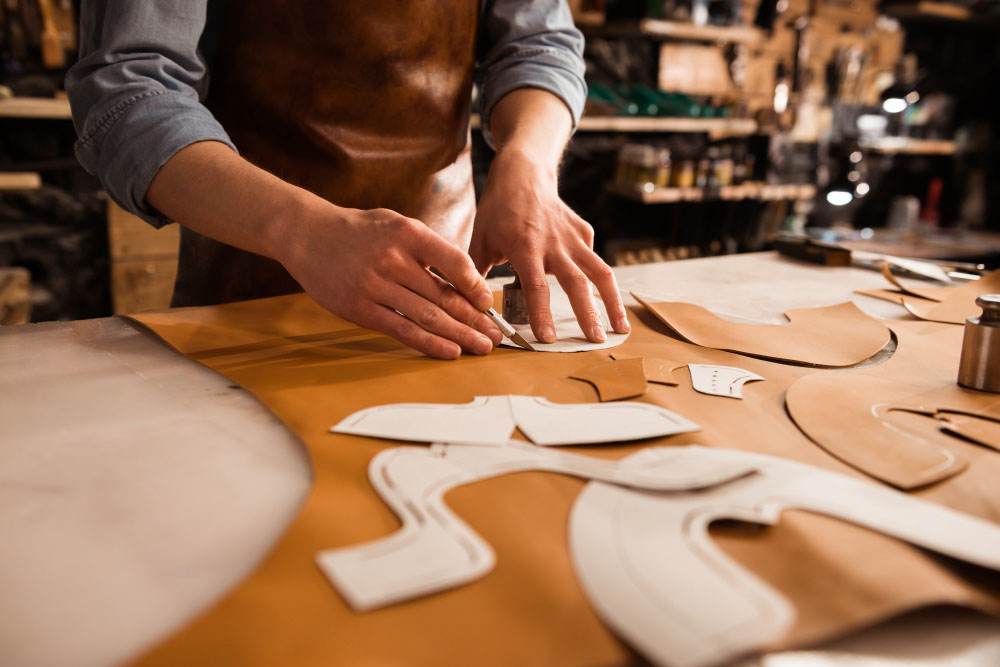 close up shoemaker measuring cutting leather Página de inicio